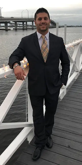 A man in suit and tie standing on pier.